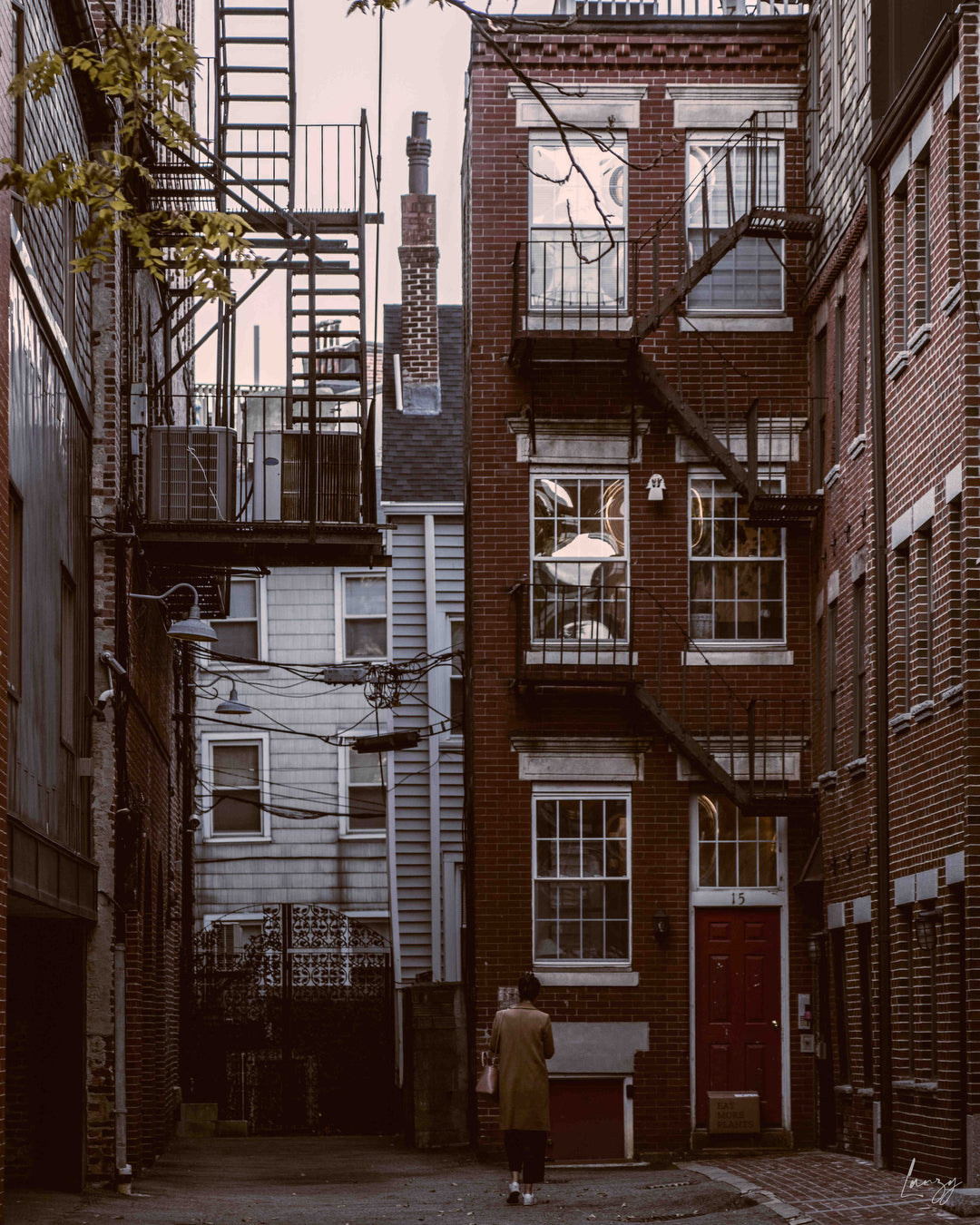 woman in a trench coat in front of a red door in the north end